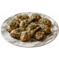 Marble plate with grilled chicken drumsticks garnished with herbs on a white background