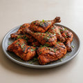 Platter of grilled chicken drumsticks with herbs on a white background