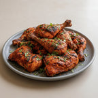 Platter of grilled chicken drumsticks with herbs on a white background